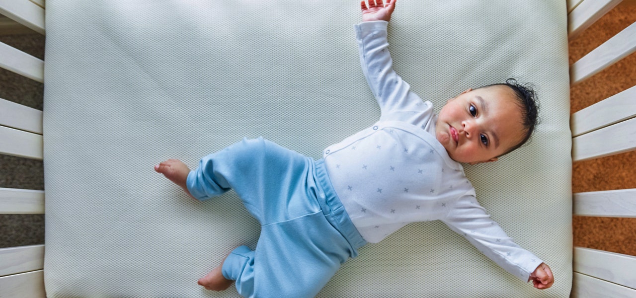 Baby lying wide awake and looking content in their crib