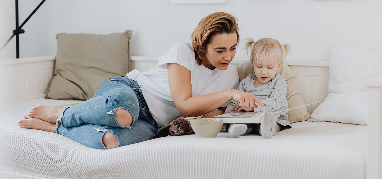 Mother and toddler looking at a picture book on a twin mattress