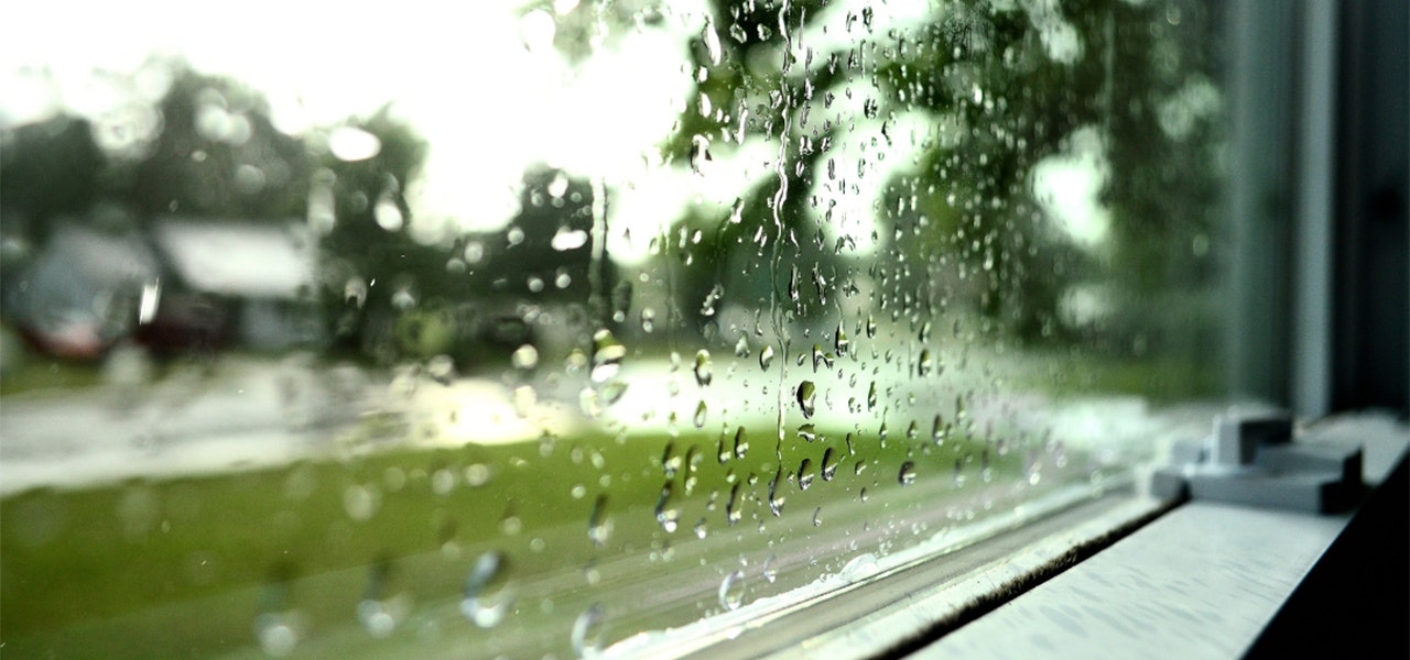 Raindrops dripping down a window showing a dreary sky