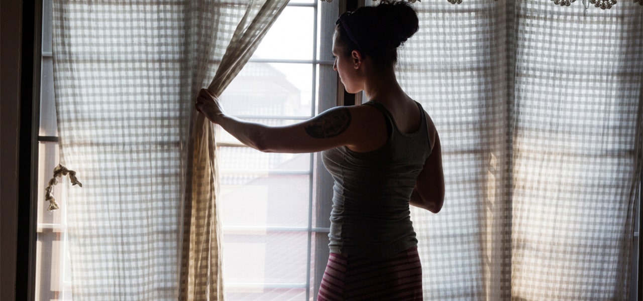 Woman opening a curtain to let in some natural light