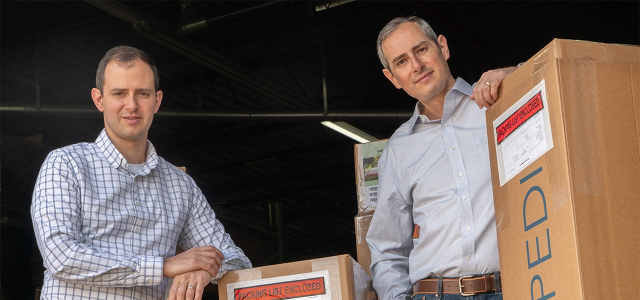 Jason and Jeff Cik, Barry's sons and Naturepedic co-owners, standing with Naturepedic mattress boxes