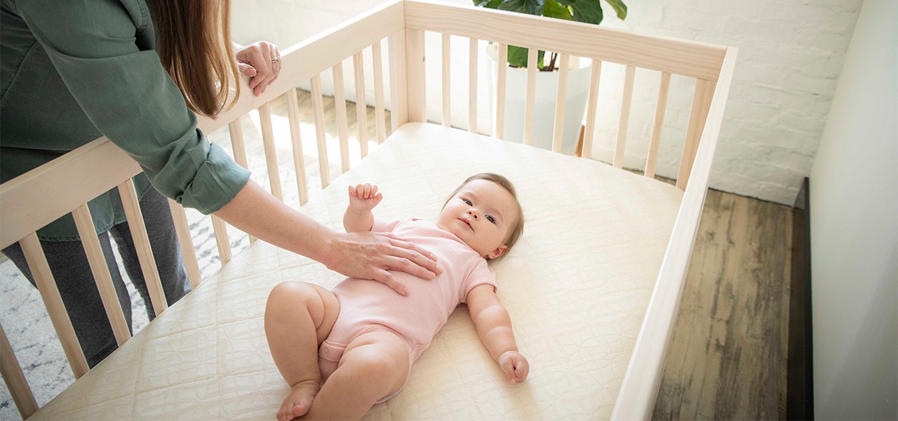 Baby lying on their back in crib and looking up at their mother