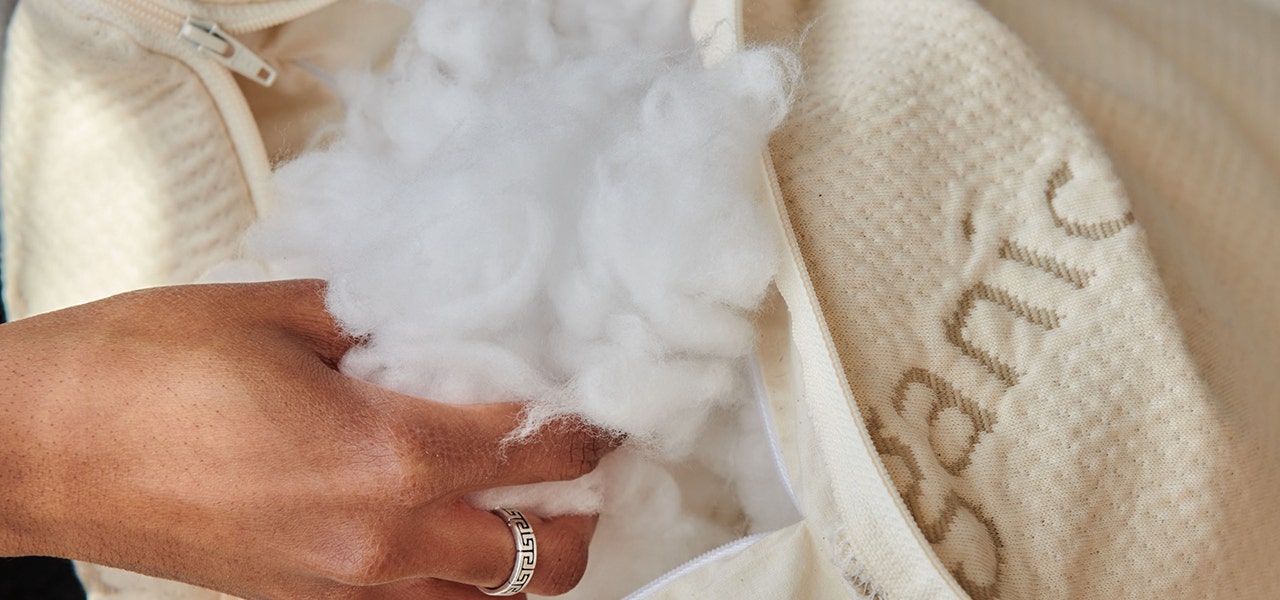 Woman fluffing non-toxic pillow fill materials inside organic cotton encasement