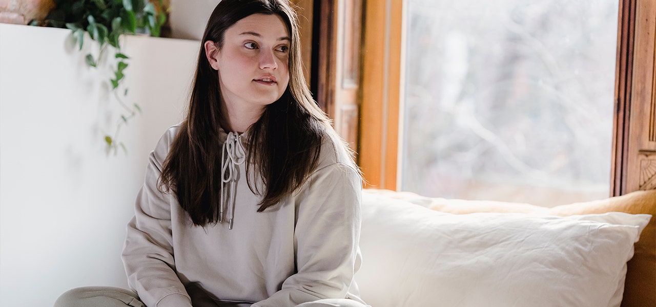Woman sitting up in bed and leaning on her body pillow
