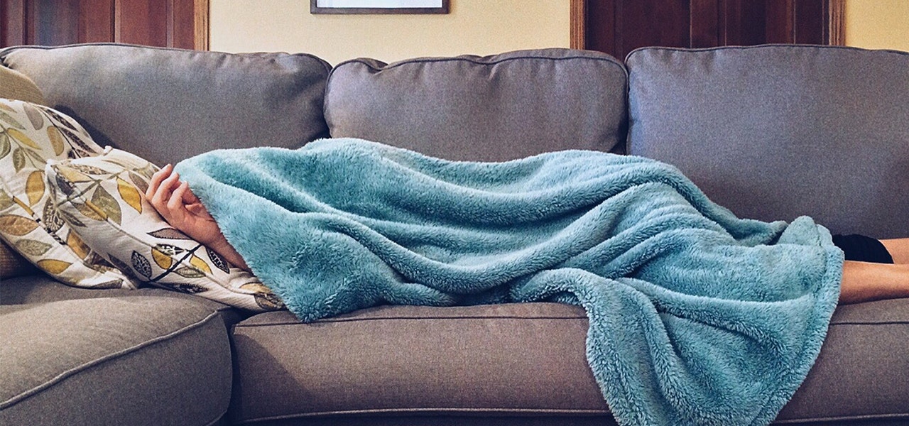 Person sleeping on the couch undef a blanket