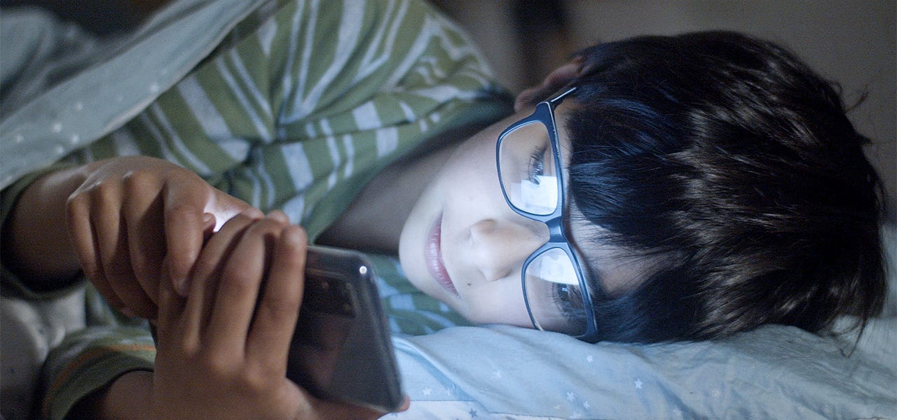 Person lying in bed and scrolling through their phone