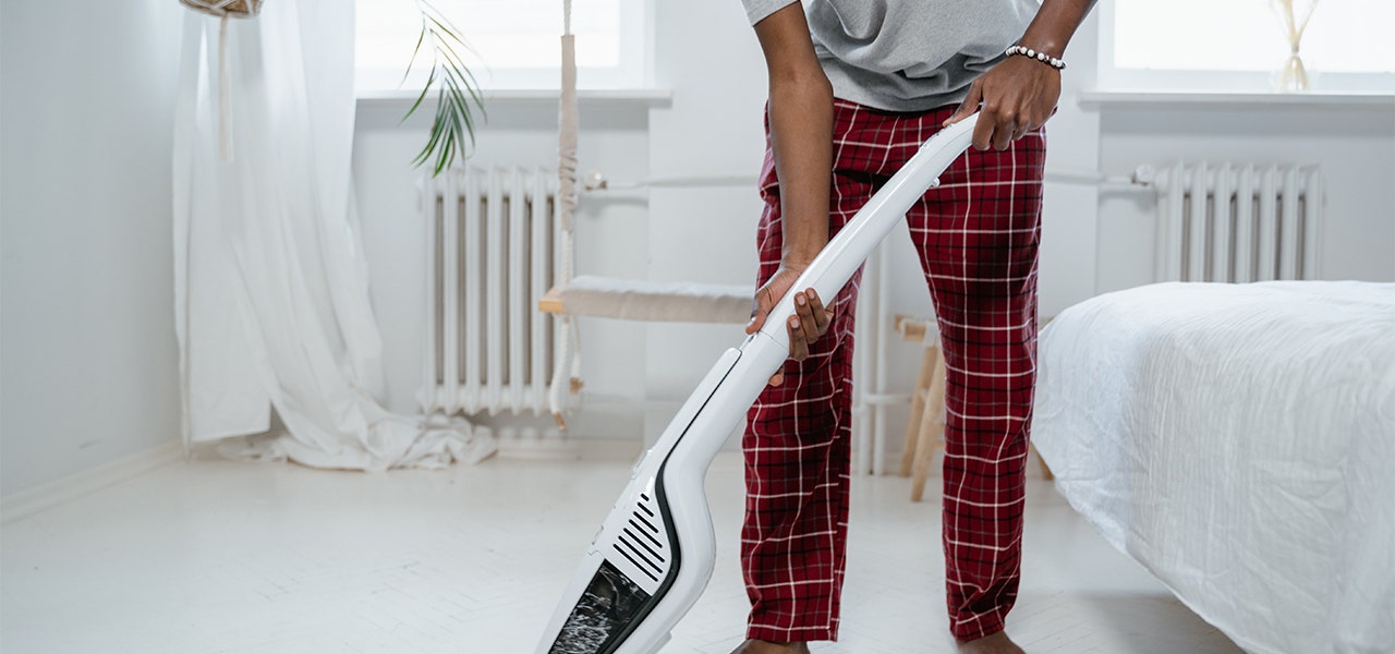 Man vacuuming his bedroom carpet in his PJs