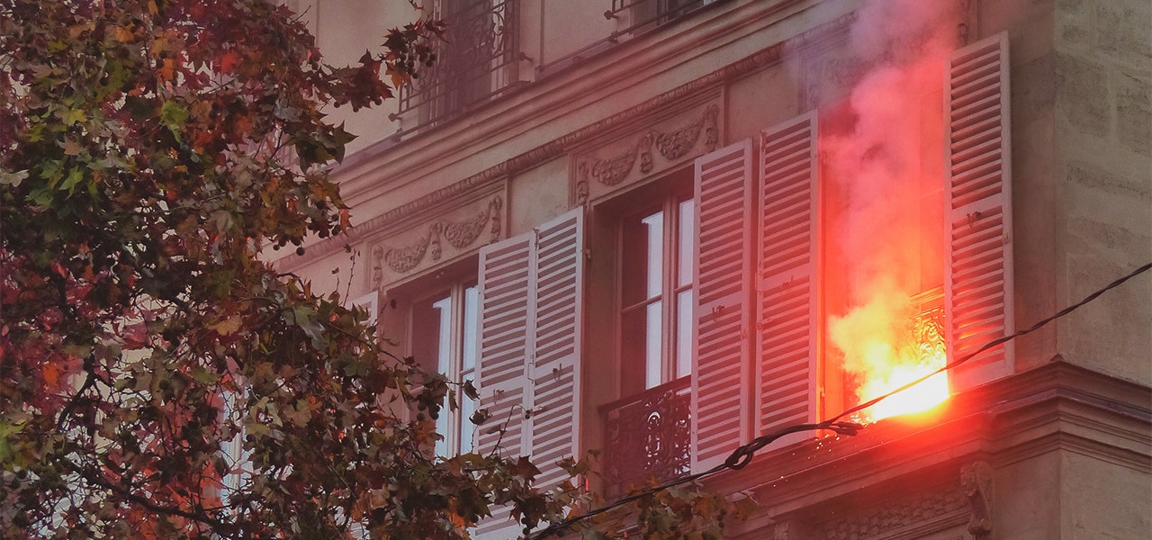 Appartment building on fire with flames coming out of a unit's window