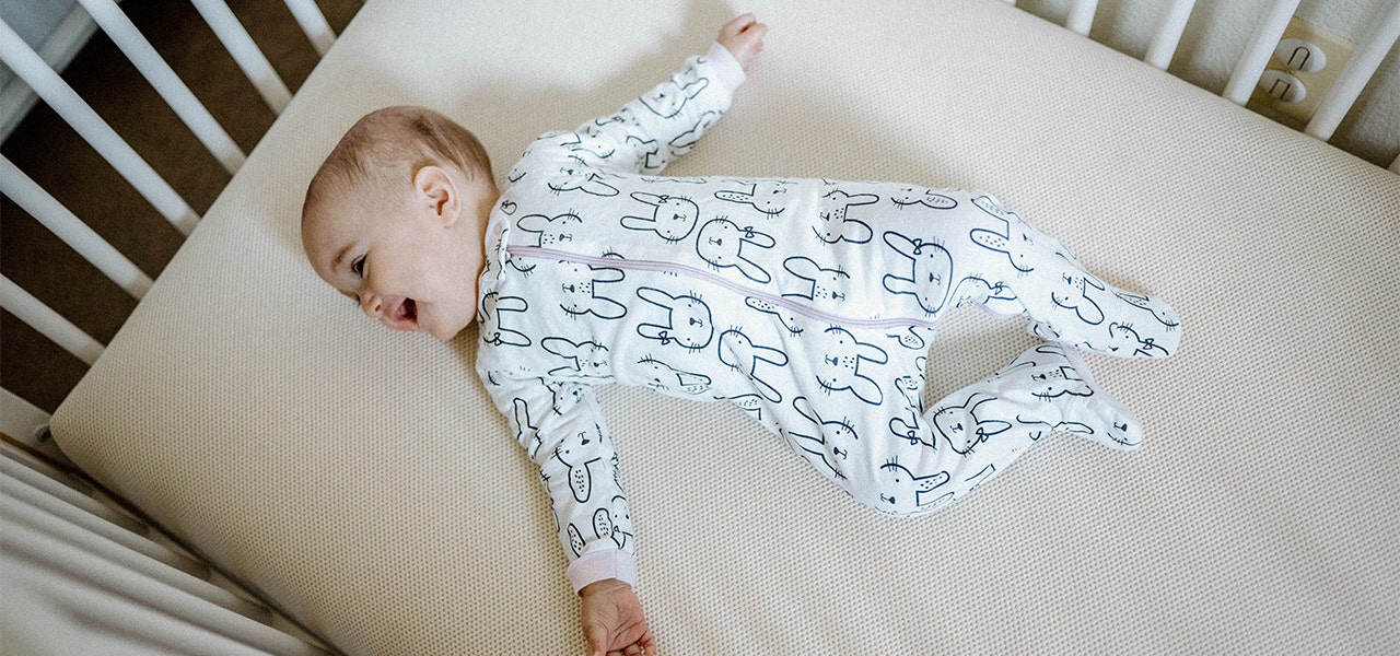 Smiling baby lying on a Naturepedic organic mattress