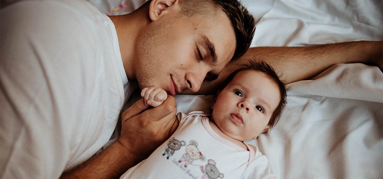 Father snuggling his baby in bed together