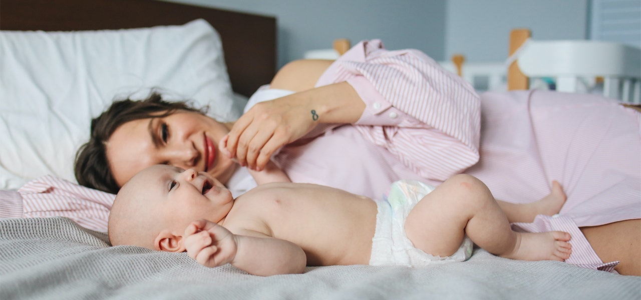 Baby keeping cool in just a diaper, playing with their mom indoors