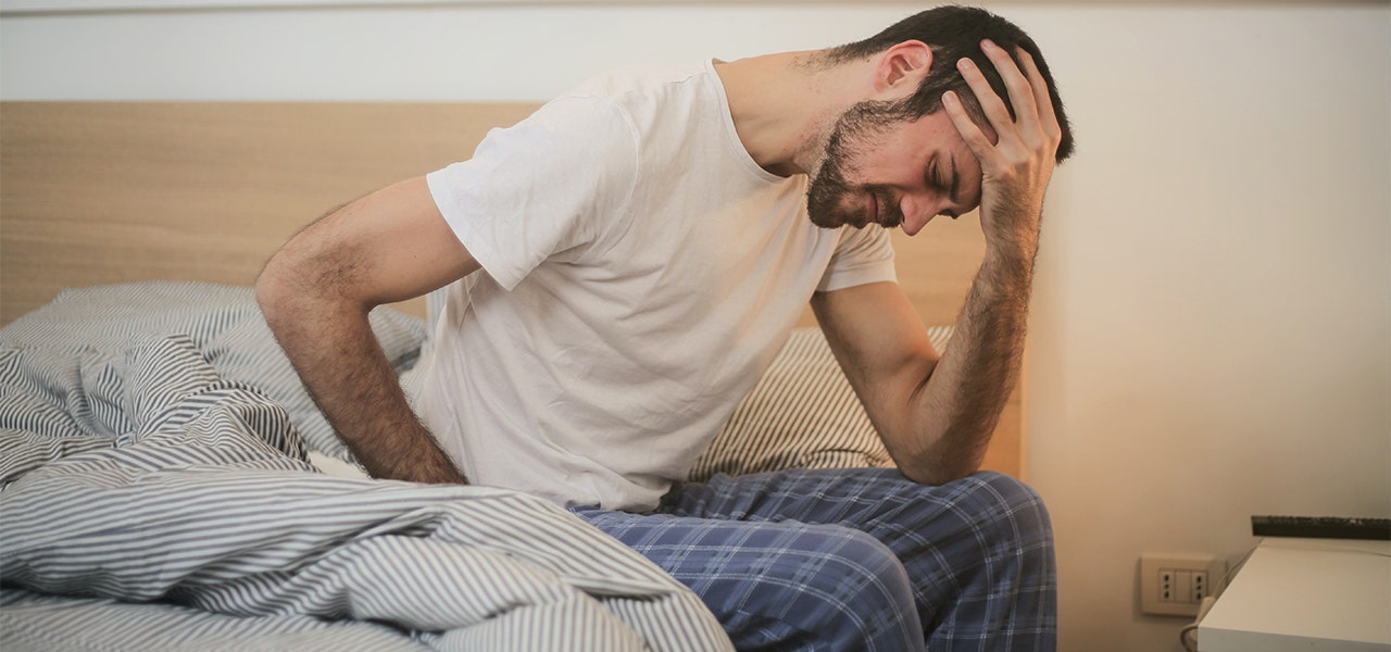Man waking up in the morning with aches and pains from a mattress without support