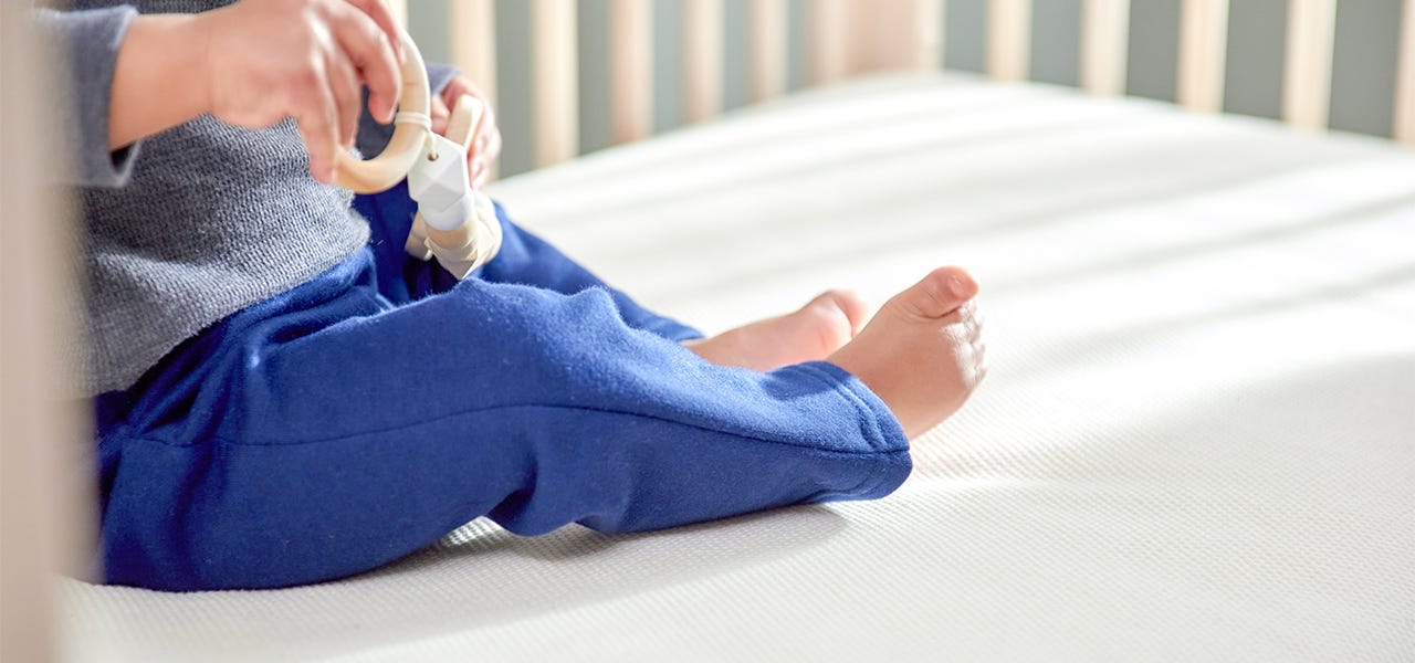 Baby sitting up on a Naturepedic organic crib mattress