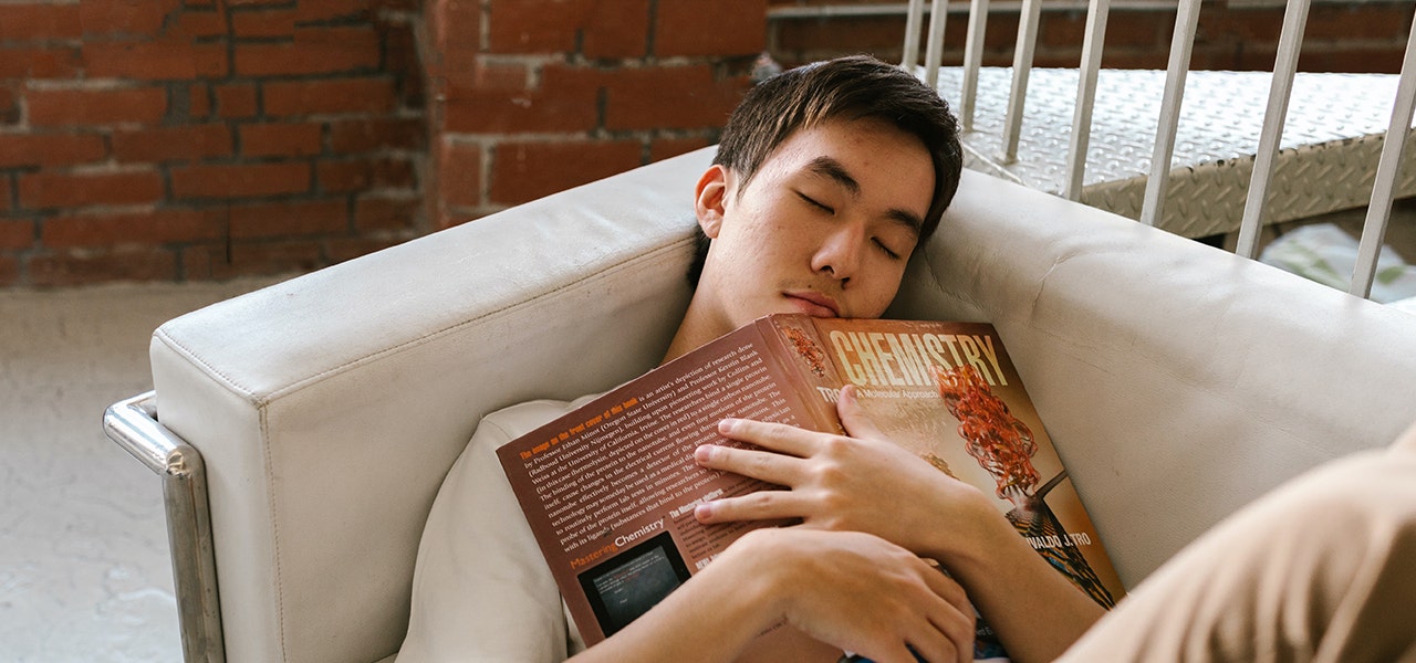 Teen boy sleeping on the couch with his homework over his chest