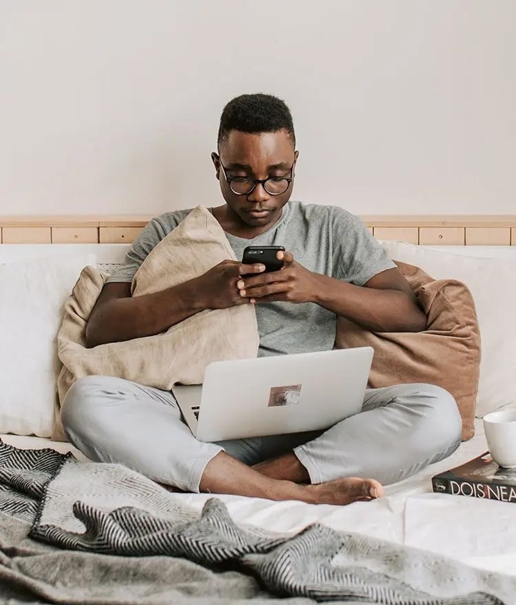 man sitting on phone on naturepedic organic mattress