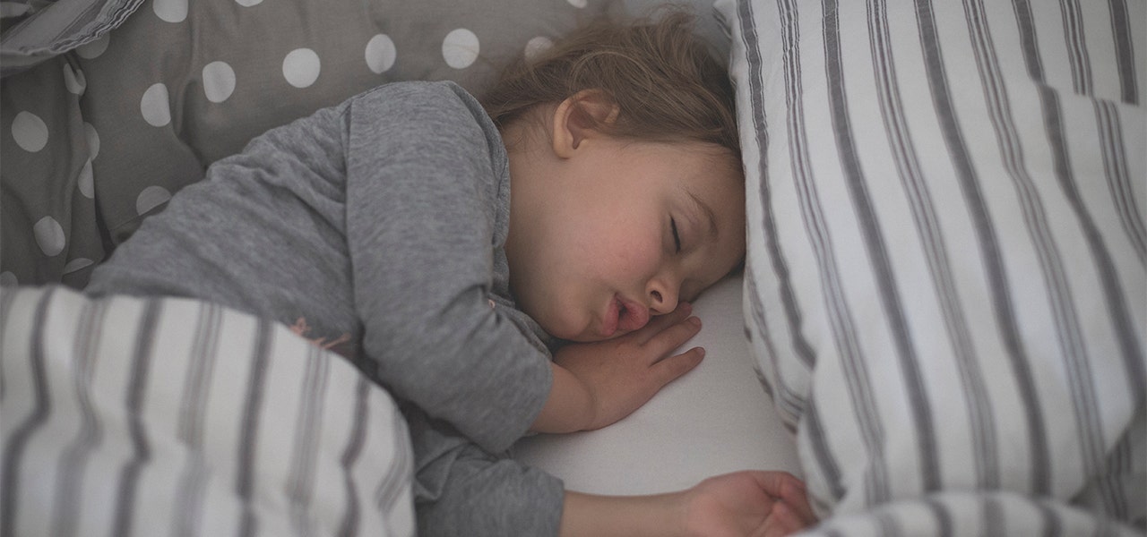 Toddler sleeping soundly in her bed in the morning hours