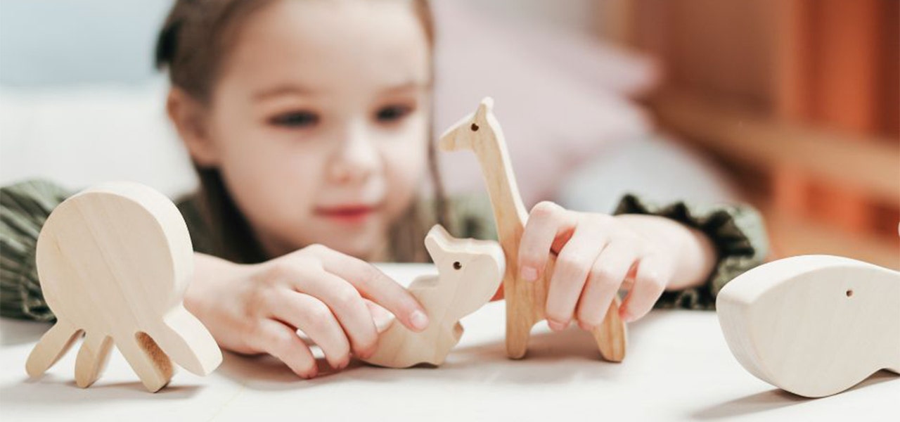 Young girl playing with small wooden toys