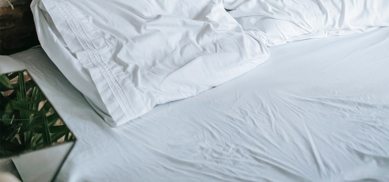 Unmade bed with white bedding