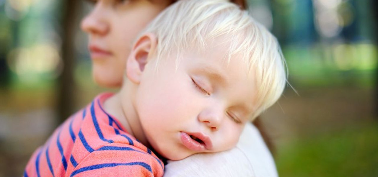 Toddler sleeping in his mother's arms