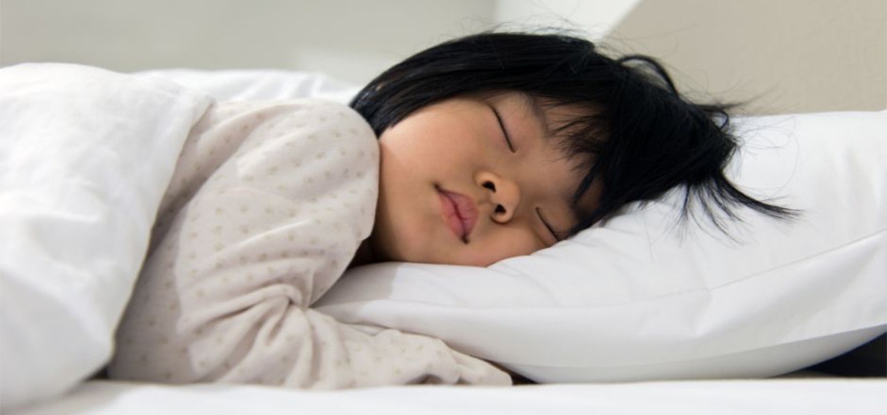 Toddler sleeping soundly in a big kid bed