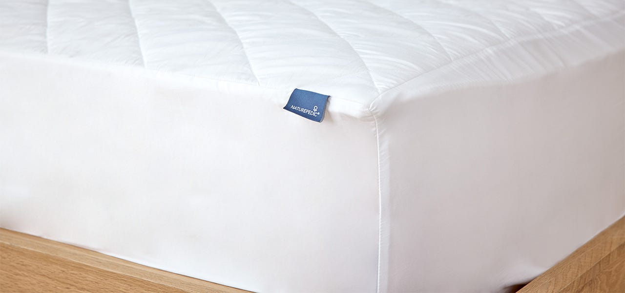 bed with naturepedic organic mattress protector pad on it