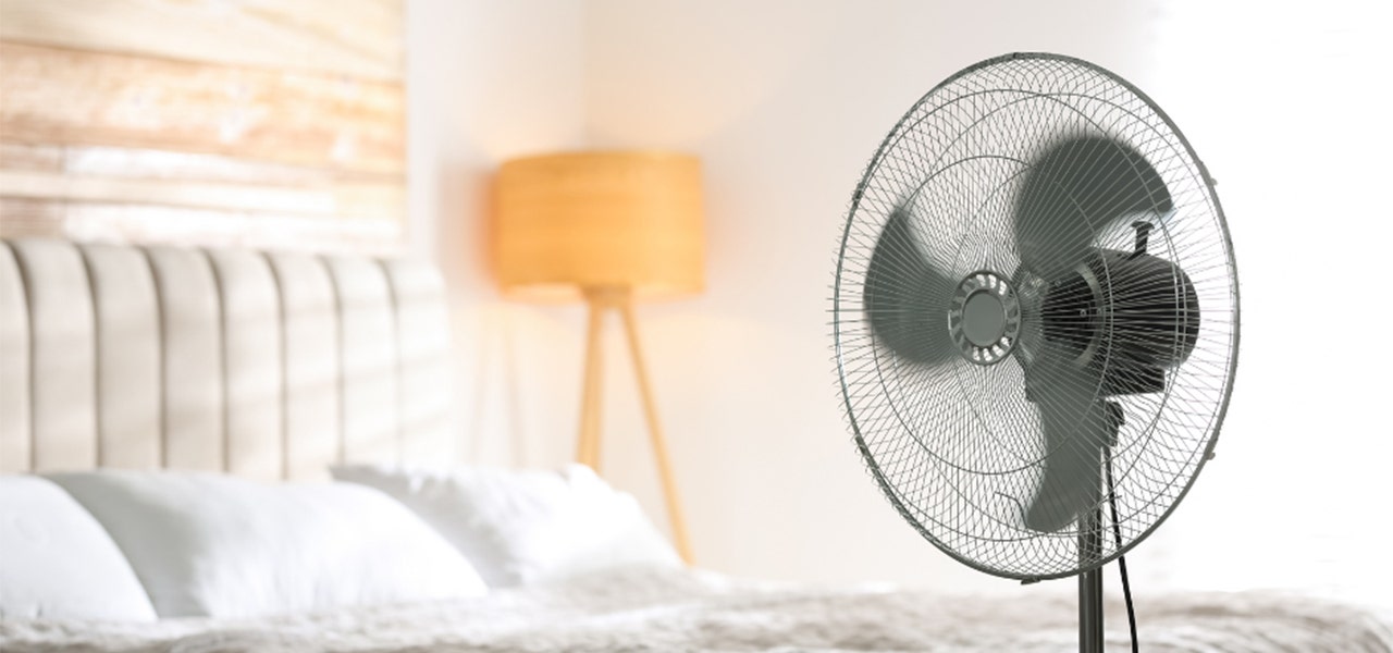 standing fan blowing in bedroom