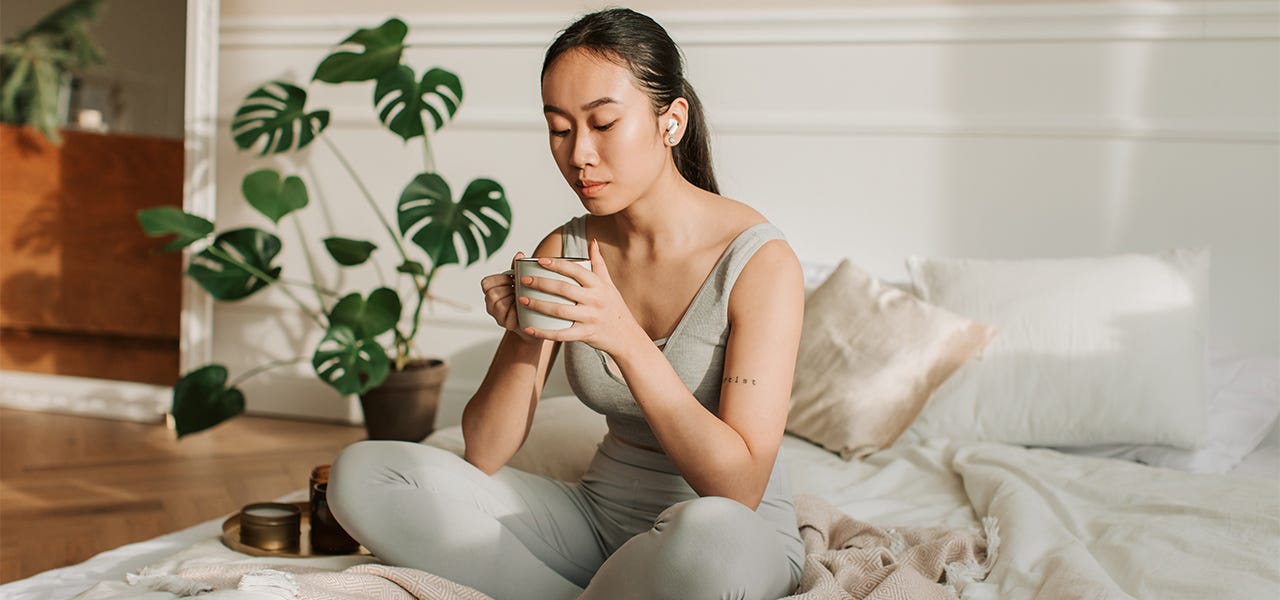 woman holding a mug on a bed