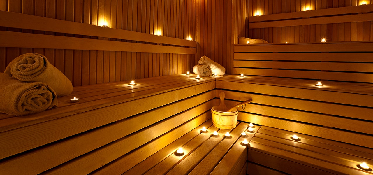 sauna with candles and towels on wooden benches