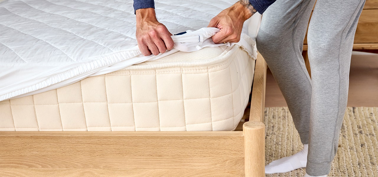 person making their bed with a naturepedic organic waterproof mattress protector