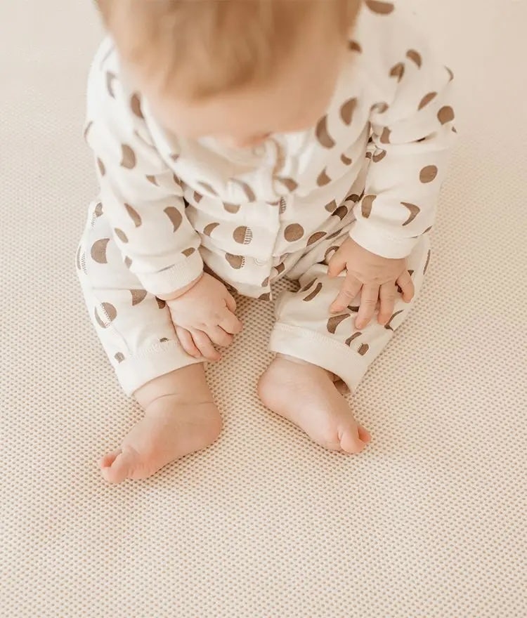 feet of baby who is sitting on naturepedic breathable organic crib mattress