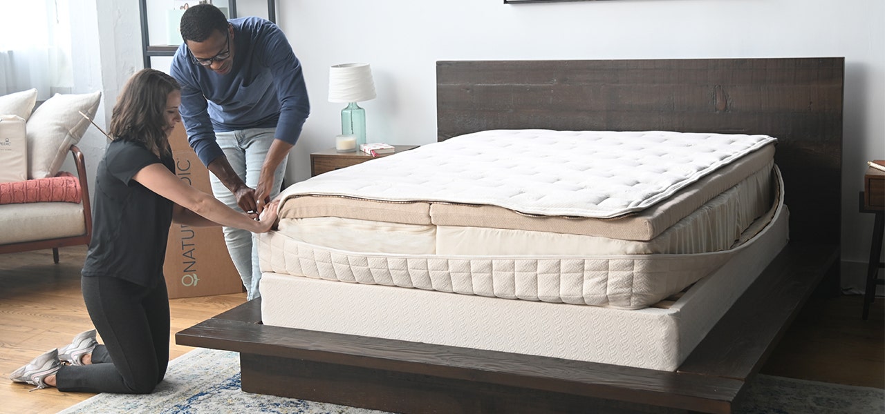 couple zipping the cover of an EOS custom organic mattress
