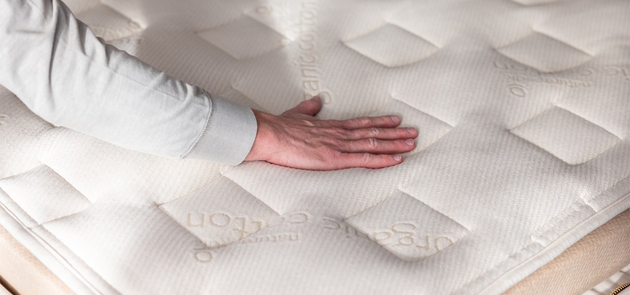 hand pressing down on naturepedic mattress