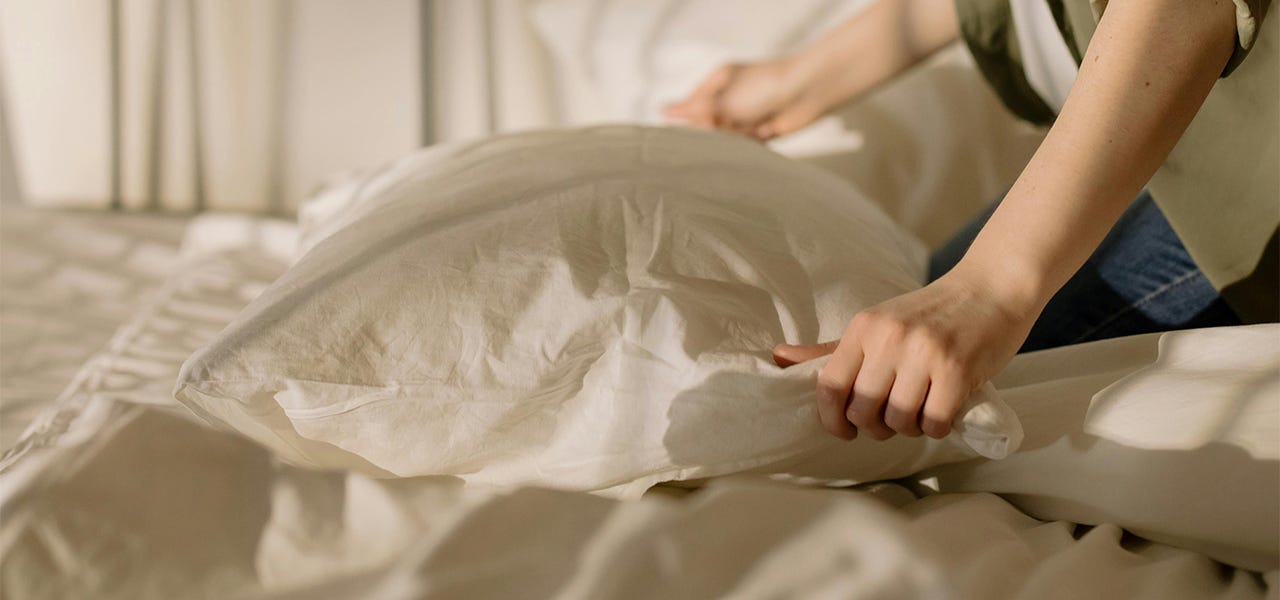 Person fluffing an old pillow