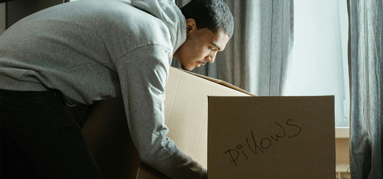 Man holding box of old pillows to donate