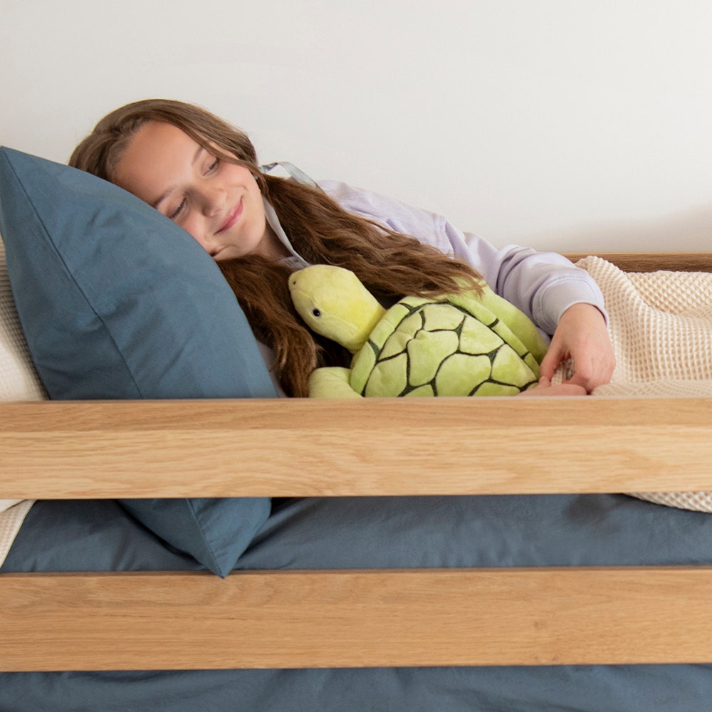Girl snuggled up in bed on percale sheets