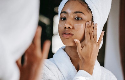 Woman applying lotion to her face after a shower